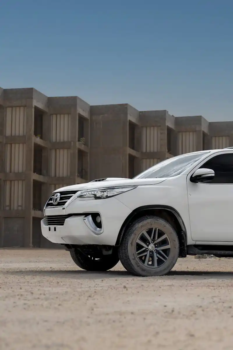 A white Toyota SUV parked in front of a concrete structure during sunset, highlighting its rugged design.